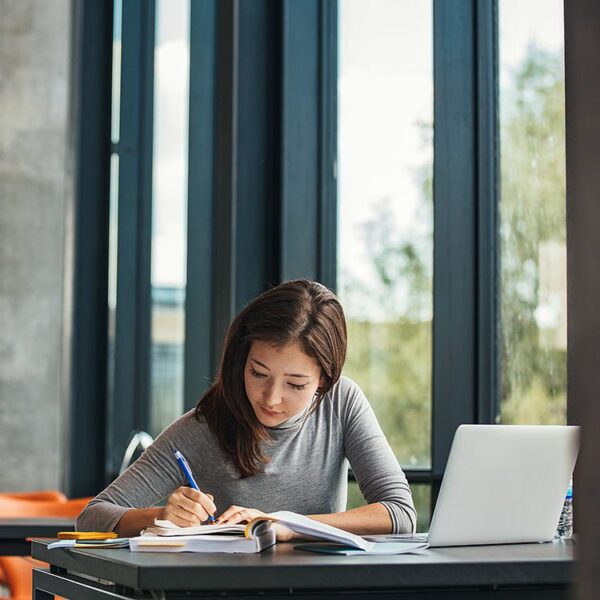 Woman taking notes in her notebook while studying.