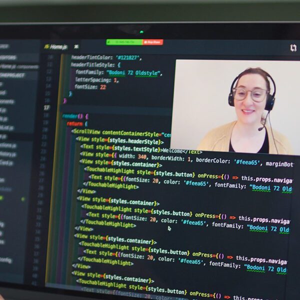 Woman video conferencing with someone while they are programming on their computer.